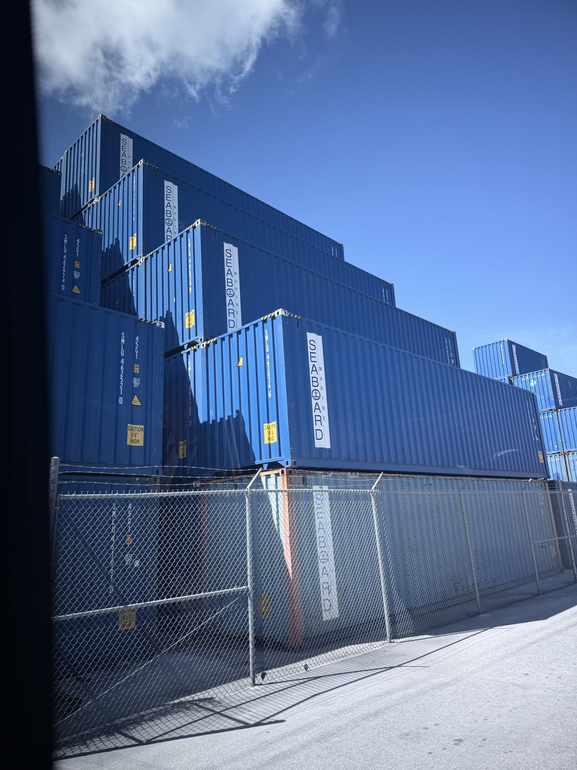A striking upward shot of shipping containers stacked at PortMiami, illustrating the scale and importance of cargo handling in regional and global logistics.